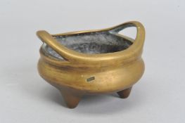 A CHINESE POLISHED BRONZE TRIPOD CENSER, 18th / 19th Century, looped handles, cast mark to