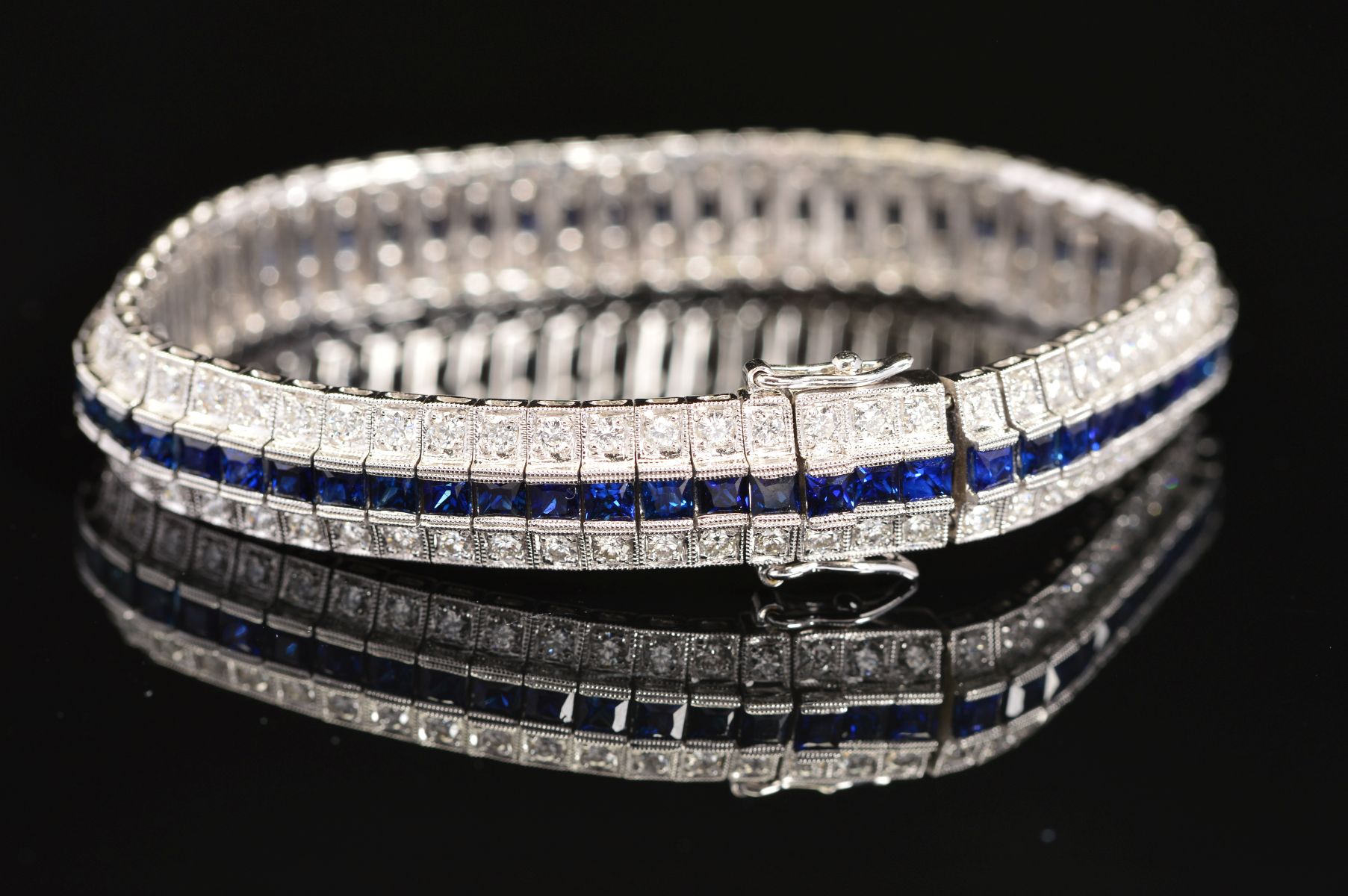 A MODERN SAPPHIRE AND DIAMOND LINE BRACELET, centring on a line of calibre square cut blue