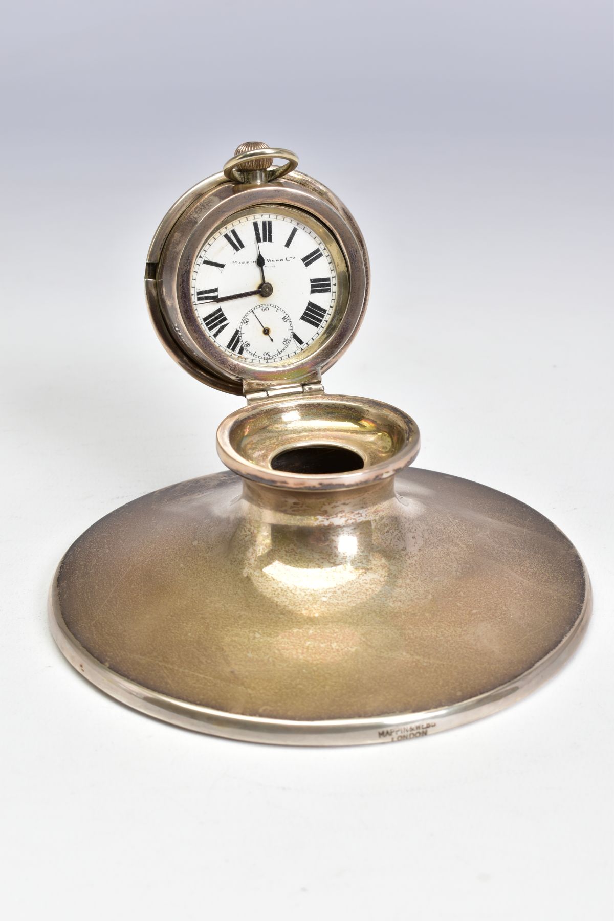 AN EDWARDIAN SILVER CAPSTAN INKWELL, the hinged cover fitted with a top wind pocket watch, the white