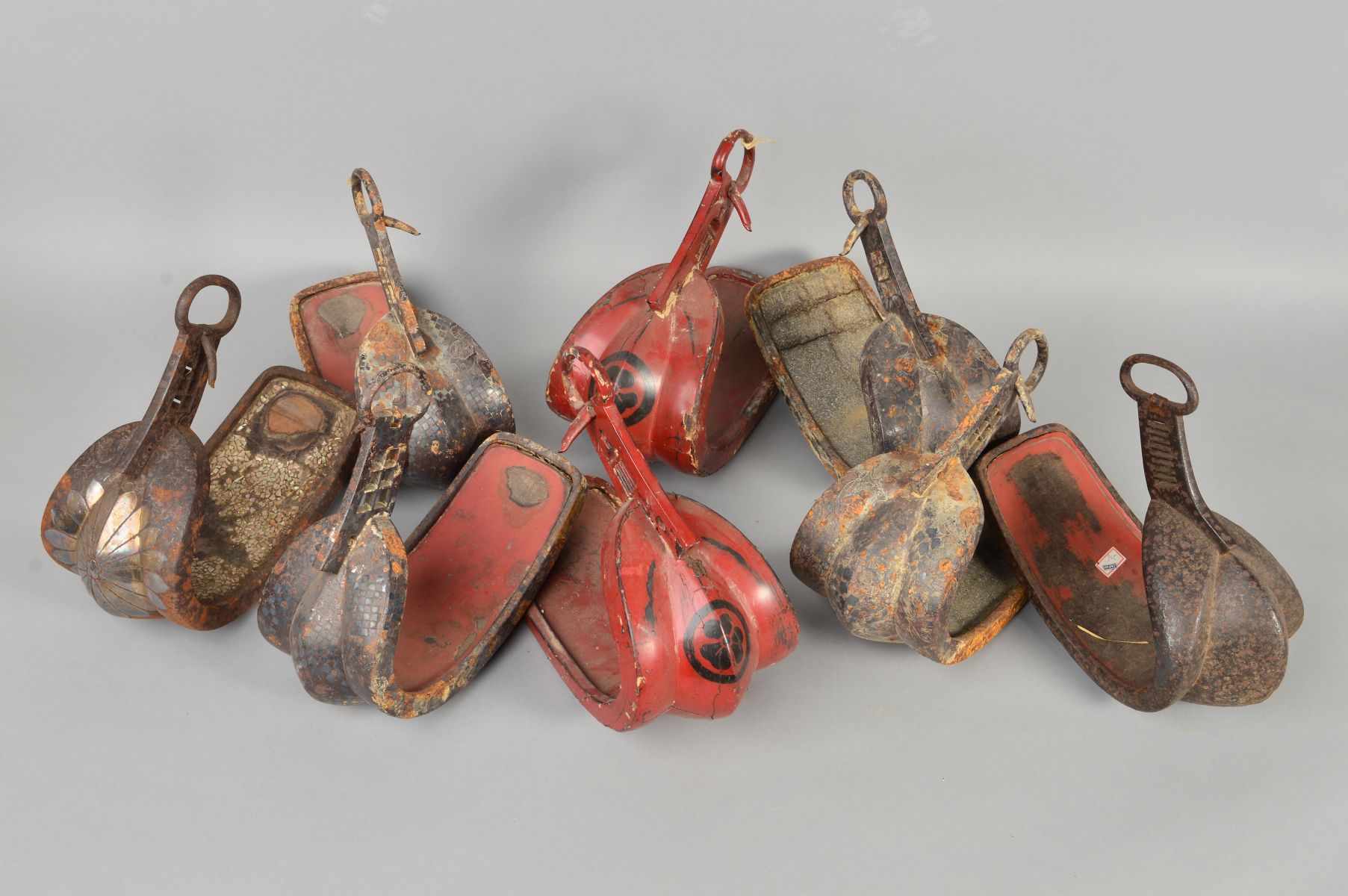THREE PAIRS OF METAL AND RED LACQUERED ASIAN STIRRUPS, together with two other Persian stirrups