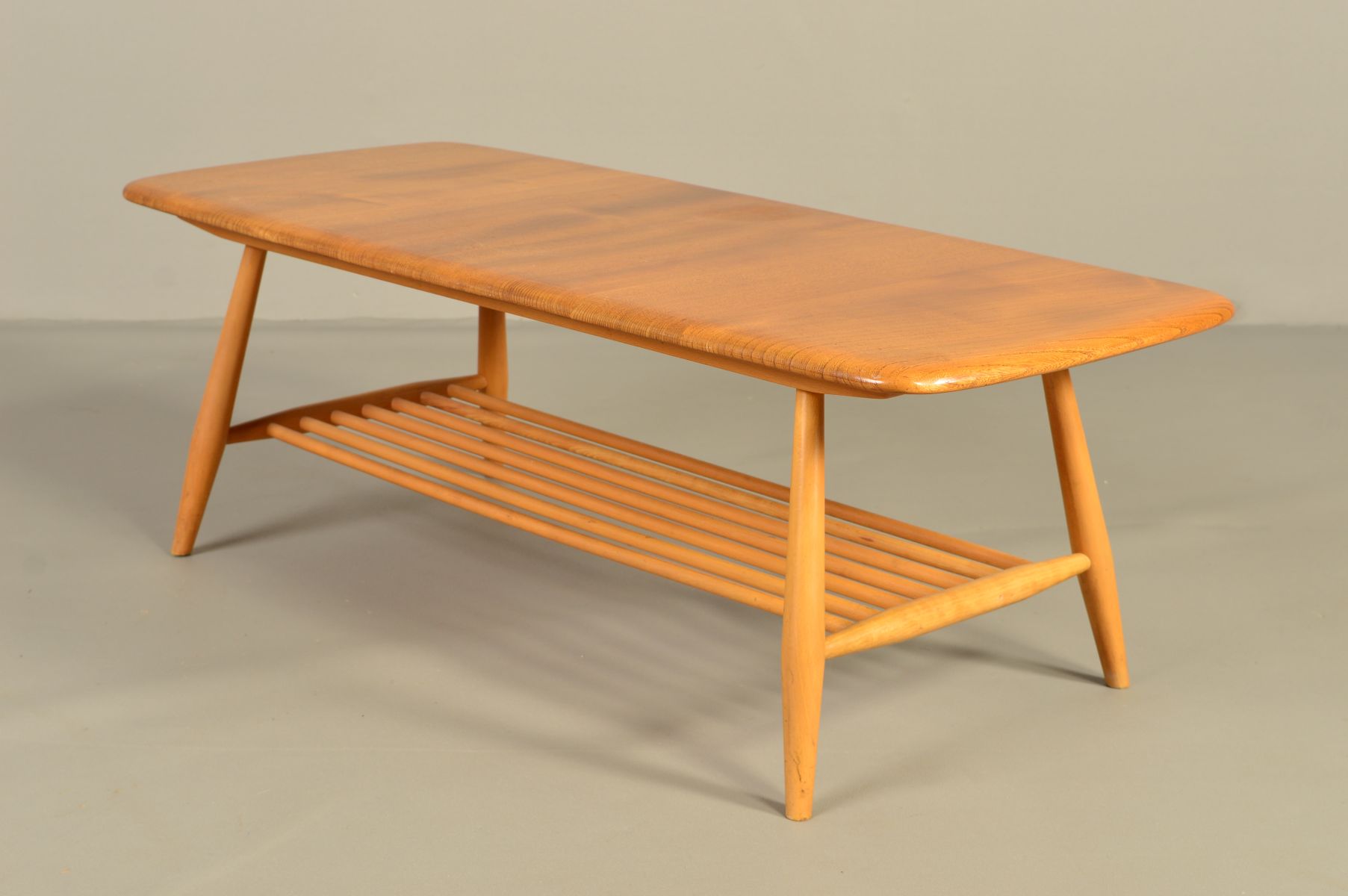 AN ERCOL BLONDE ELM RECTANGULAR COFFEE TABLE, on four beech tapering legs united by a spindled - Image 6 of 6