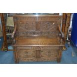 A REPRODUCTION OAK HALL SETTLE, with four carved panels, hinged storage compartment flanked by