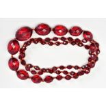 A FACETED RED BEAD NECKLACE, designed as a single row of graduated oval faceted red beads