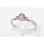 A GEM SET RING, designed as a central oval pink gem, assessed as topaz, flanked by brilliant cut