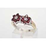 A 9CT GOLD GARNET AND DIAMOND RING, designed as two flowers each with six circular cut garnets