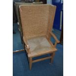 AN EARLY 20TH CENTURY LIGHT OAK ORKNEY CHAIR, the curved woven straw back flanked by open arm rests,