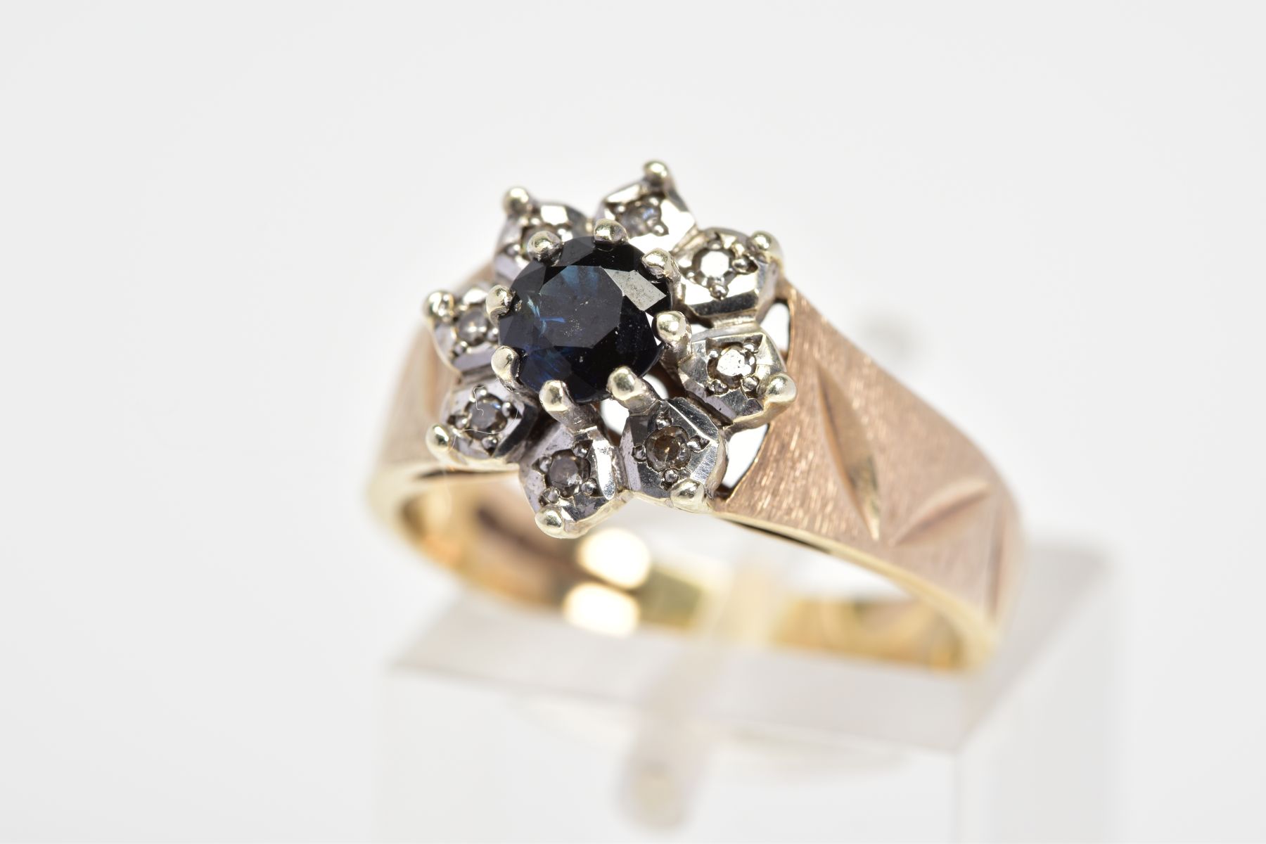 A 9CT GOLD SAPPHIRE AND DIAMOND RING, the tiered cluster designed as a central circular sapphire