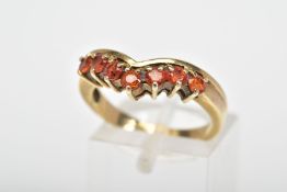 A 9CT GOLD ORANGE TOPAZ RING, the v-shape ring claw set with seven circular orange topaz stones,