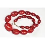 A RED PLASTIC BEAD NECKLACE, comprising of a graduated row of oval beads, measuring 12mm to 30mm,