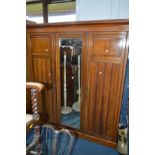 AN EDWARDIAN WALNUT MIRRORED TRIPLE DOOR WARDROBE, the left door with four linen slides and three