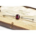 AN EARLY 20TH CENTURY GEM SET BAR BROOCH, designed with a central rectangular cut garnet, flanked by