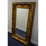 A LARGE MODERN FOLIATE GILT WOOD BEVELLED EDGE RECTANGULAR WALL MIRROR, 165CM X 105CM (sd)