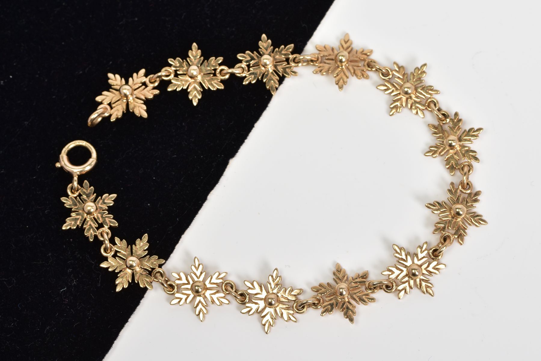 A 9CT GOLD SNOWFLAKE LINK BRACELET, made up of thirteen snowflakes with spherical centres, fitted