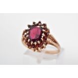 A 9CT GOLD GARNET RING, designed as an oval garnet within a circular garnet surround to the rope