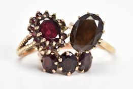 THREE GEM SET RINGS, the first set with an oval smoky quartz, the second an oval garnet within a