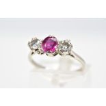 A RUBY AND DIAMOND RING, set with a central oval cut ruby flanked with brilliant cut diamonds,