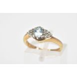 A 9CT GOLD AQUAMARINE AND DIAMOND RING, the central oval aquamarine flanked by a triangle cluster of