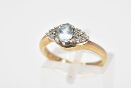 A 9CT GOLD AQUAMARINE AND DIAMOND RING, the central oval aquamarine flanked by a triangle cluster of