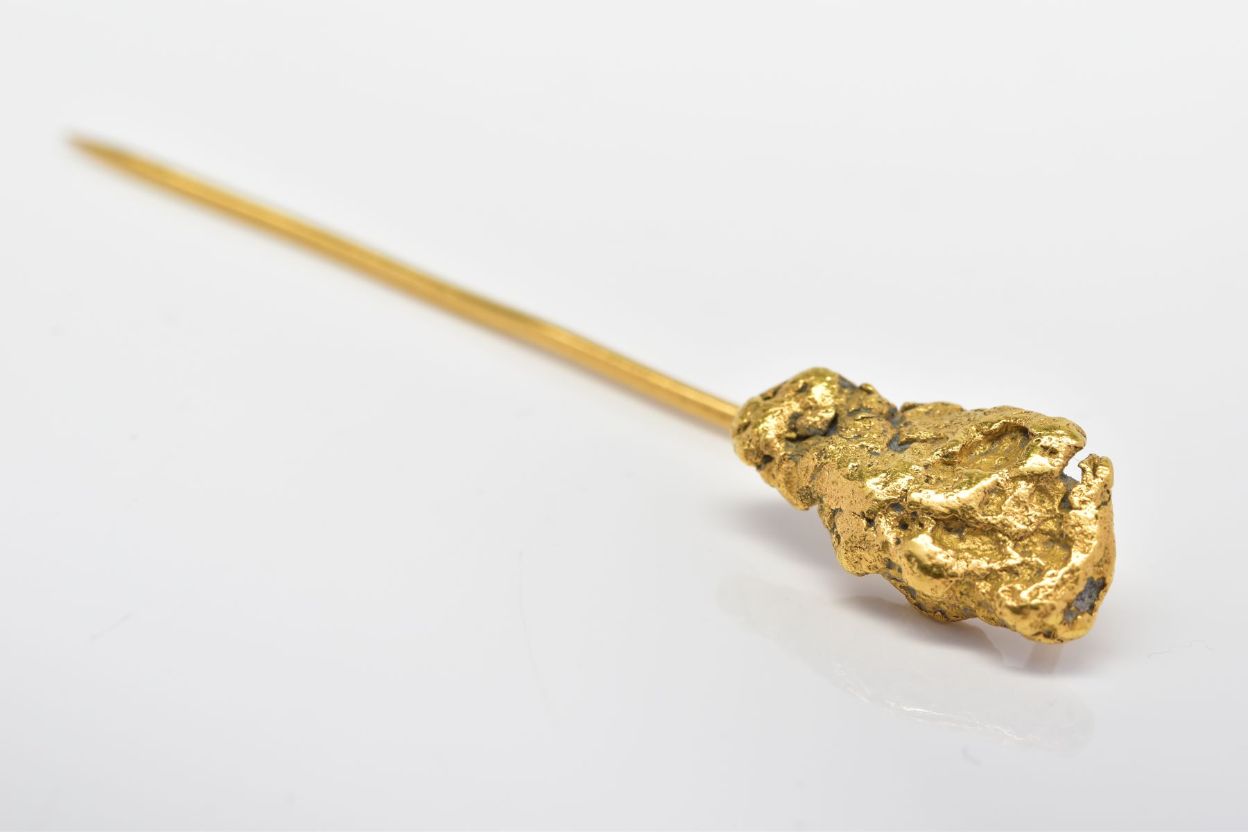 A NUGGET STICKPIN, the terminal designed as a textured gold nugget to the plain pin, tests as