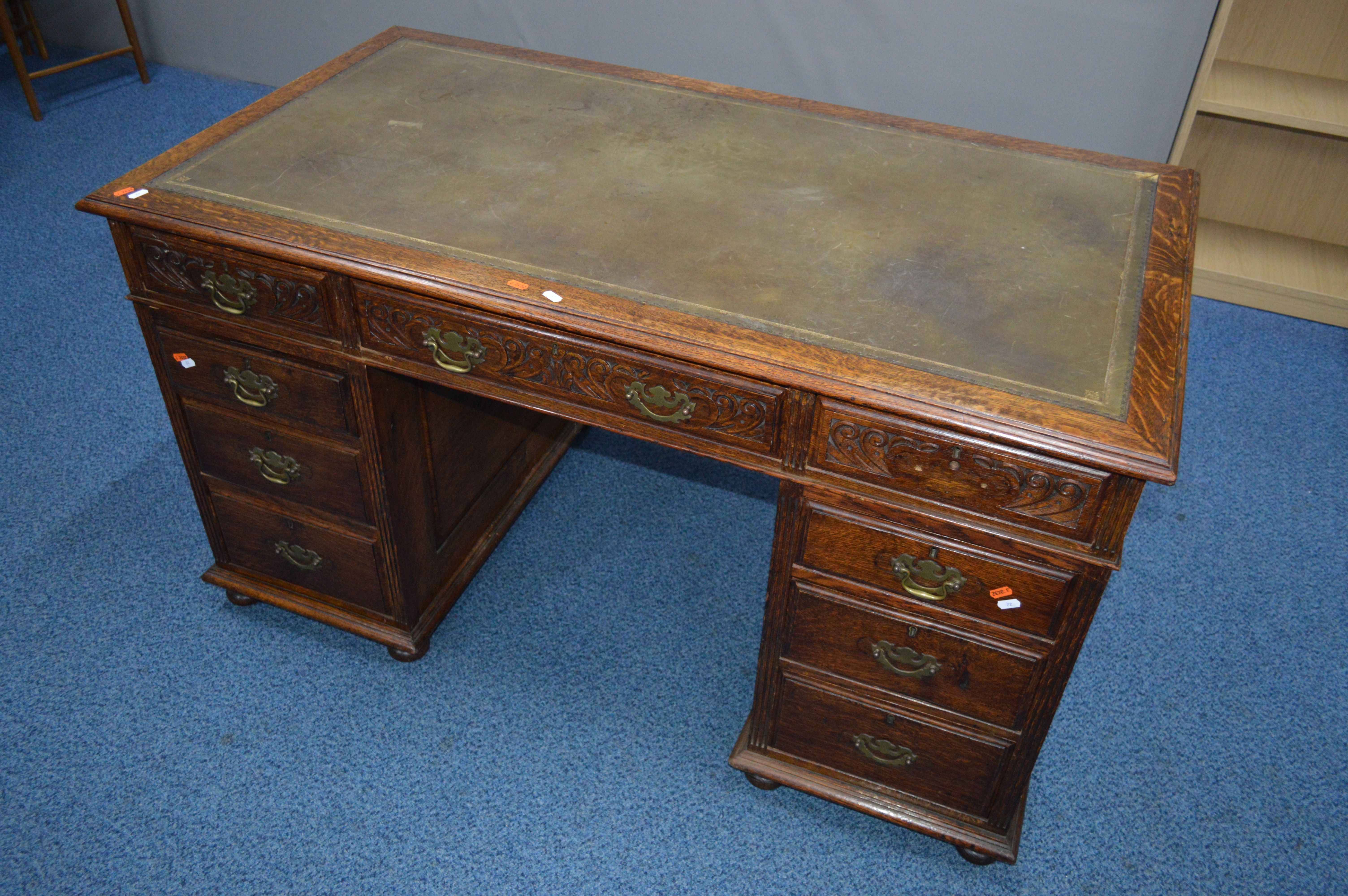 AN EARLY 20TH CENTURY CARVED OAK PEDESTAL DESK, dark green gilt tooled leather inlay top and nine