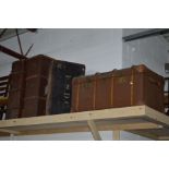 A LEATHER AND WOODEN BOUND SHIPPING TRUNK together with two travelling trunks and a leather and