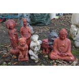 A COLLECTION OF COMPOSITE RED GROUND ORIENTAL GARDEN FIGURES, to include a Buddha, two dogs of fo,