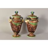 A PAIR OF MAJOLICA URNS AND COVERS, having animal head handles, embossed children at play