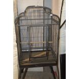 A MODERN METAL PARROT CAGE with domed top standing on curved legs and wheels, height 168cm x width