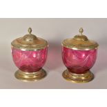 A PAIR OF CRANBERRY COLOURED BISCUIT BARRELS (?), with plated covered and plated bases, heights
