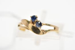 A 9CT GOLD SAPPHIRE DRESS RING, of asymmetric design and split front band, diagonally set with two
