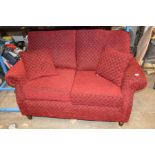 A DEEP RED UPHOLSTERED TWO SEATER SOFA, width 150cm
