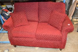 A DEEP RED UPHOLSTERED TWO SEATER SOFA, width 150cm