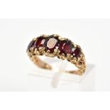 A 9CT GOLD RED GLASS RING, designed as five graduated oval cut red pastes within claw settings to