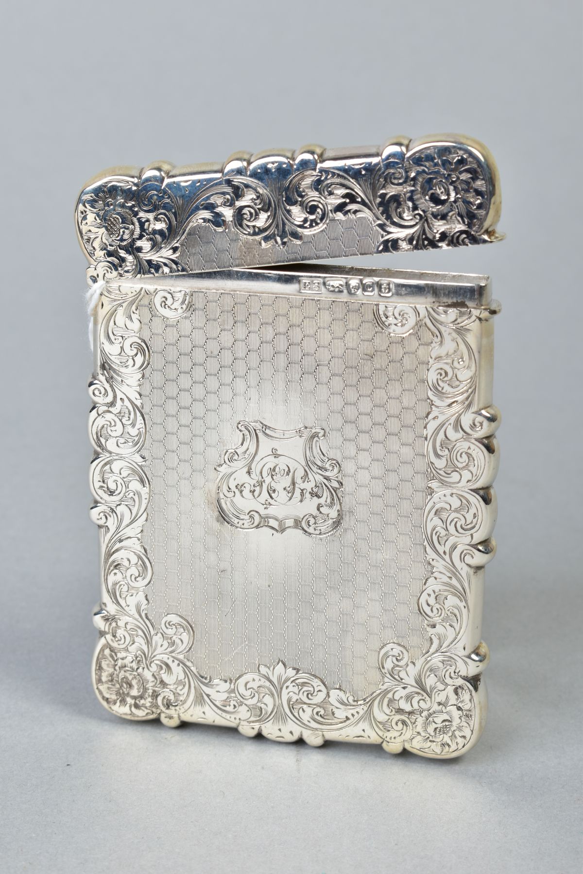 A MID VICTORIAN SILVER CARD CASE OF WAVY RECTANGULAR OUTLINE, foliate engraved and engine turned