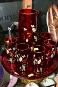 A FLORALLY ENAMELLED CRANBERRY GLASS LEMONADE SET, comprising a jug, height 25cm and five matching
