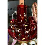 A FLORALLY ENAMELLED CRANBERRY GLASS LEMONADE SET, comprising a jug, height 25cm and five matching