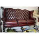 A RED LEATHER WINGED THREE SEATER SOFA, width 180cm