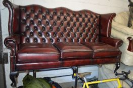 A RED LEATHER WINGED THREE SEATER SOFA, width 180cm