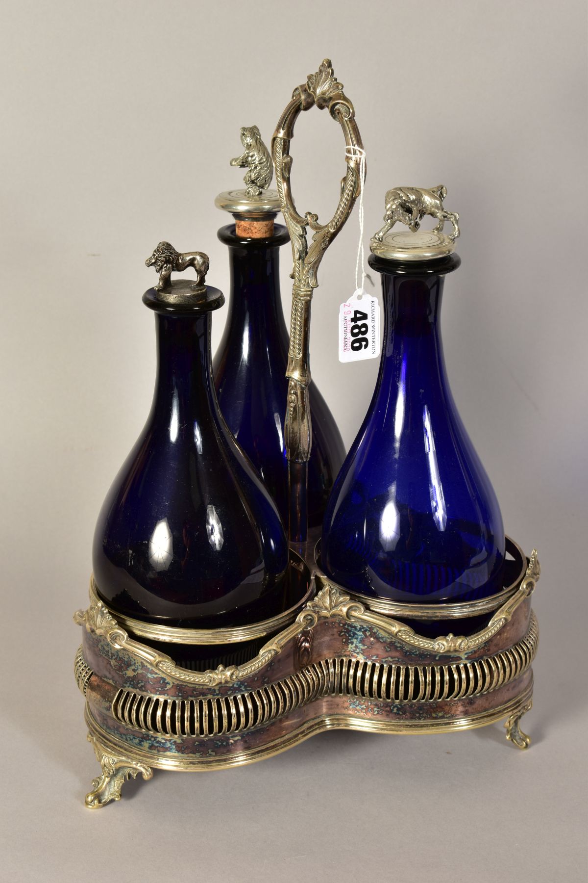 A VICTORIAN PLATED TREFOIL DECANTER STAND, containing three blue glass decanters with novelty
