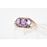 AN AMETHYST AND DIAMOND RING, designed as three oval cut amethysts within claw settings with a