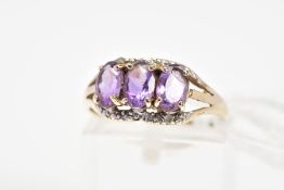 AN AMETHYST AND DIAMOND RING, designed as three oval cut amethysts within claw settings with a