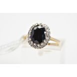 A 9CT GOLD SAPPHIRE AND DIAMOND CLUSTER RING, the central oval sapphire within a single cut
