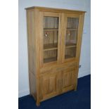 A LIGHT OAK GLAZED TWO DOOR BOOKCASE with three drawers and double cupboard doors, width 108cm x