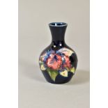 A SMALL MOORCROFT POTTERY BUD VASE, 'Orchid' pattern on blue ground, Queen Mary paper label to base,