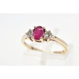 A 9CT GOLD RUBY AND DIAMOND RING, the central oval glass filled ruby flanked by brilliant cut