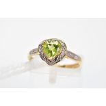 A PERIDOT AND DIAMOND DRESS RING, the heart shape peridot in a three claw setting within a