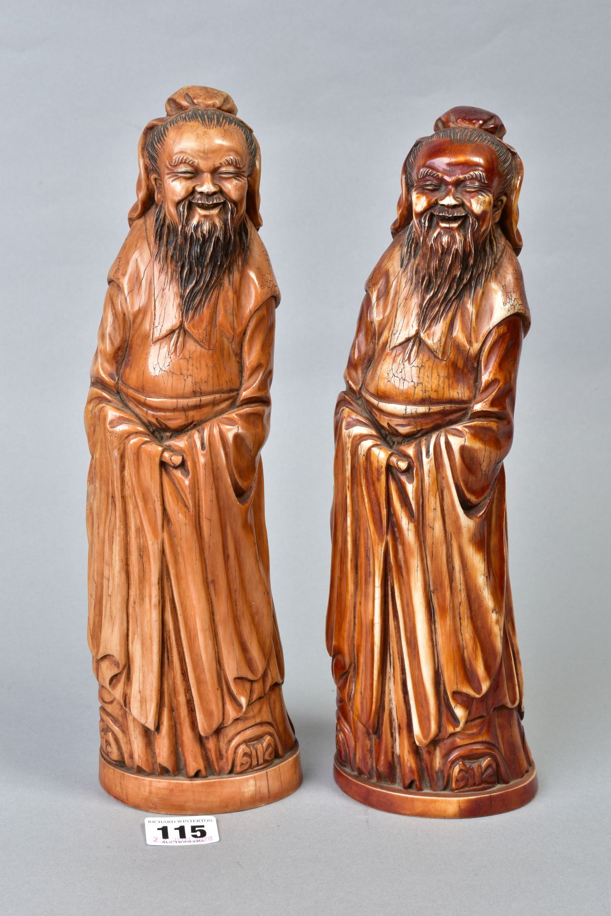 TWO NEAR IDENTICAL CHINESE CARVED AND BROWN STAINED IVORY FIGURES OF IMMORTALS, on oval bases with