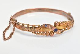 AN EARLY 20TH CENTURY 9CT GOLD GEM SET HINGED BANGLE, designed with a central tapered diagonal panel