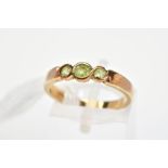 A 9CT GOLD GEM RING, designed as three graduated circular green gems assessed as peridot, in part