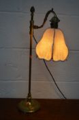 AN EARLY TO MID 20TH CENTURY BRASS TABLE LAMP with a swinging shaped arm and hanging fabric shade on